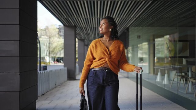 Young woman walking in the city, carrying suitcase baggage arriving to hotel. Travel vacations lifestyle