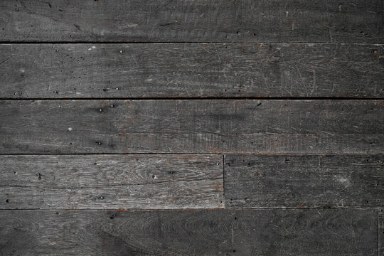 A dark, weathered, and rustic wooden planks texture background featuring visible wood grain, scratches, nail heads, and an aged surface, ideal for design, background, and 3D rendering.