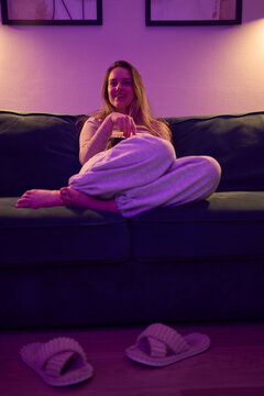 Female relaxing on sofa with popcorn in cozy dimly lit living room
