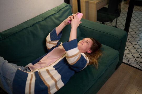 Home comfort with woman browsing smartphone on sofa