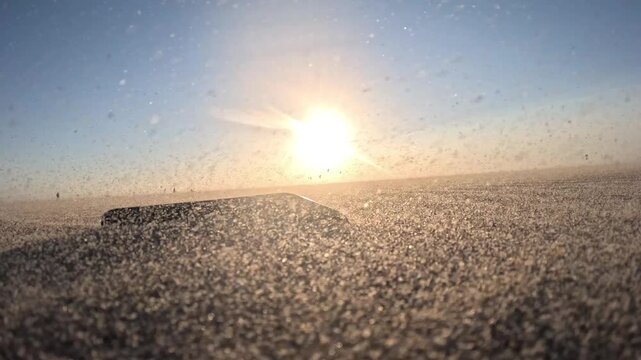 Scenic Dutch beach at golden hour with a smartphone on the sand and kitesurfers riding the North Sea