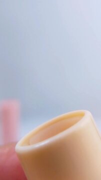Close up of lip balm with yellow packaging slowly coming out. Isolated on soft blurred white background. Beauty cosmetic product for lip care.