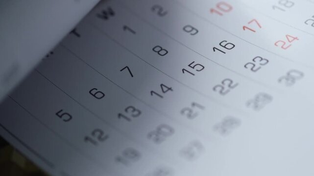 Macro view of flipping calendar pages showing dates in fast motion for time management concept