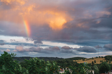 Rainbow on a stormy sky, with wind turbines and a GSM mast in the background, Kamienna Góra, Poland. © stockcrafter