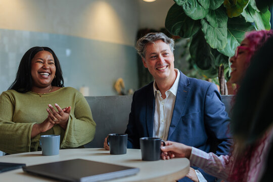 Diverse business team sharing laughter and coffee