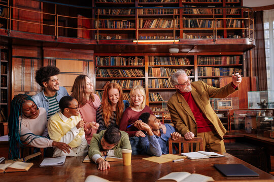 Professor and diverse students taking a selfie in library