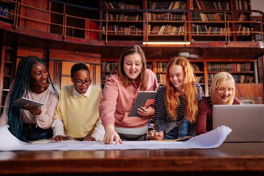 Diverse female students collaborating on a project in library