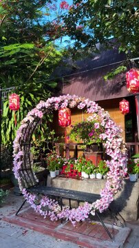 Da nang, lady buddha, garden arch featuring pink blooming flowers, a seating bench, and traditional red lanterns in an outdoor park setting