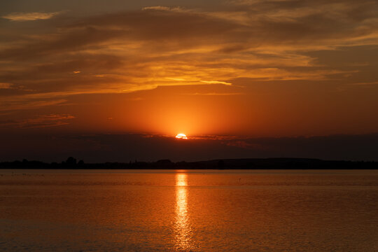Vibrant sunset reflecting on the water of Lake Morii in Bucharest, Romania