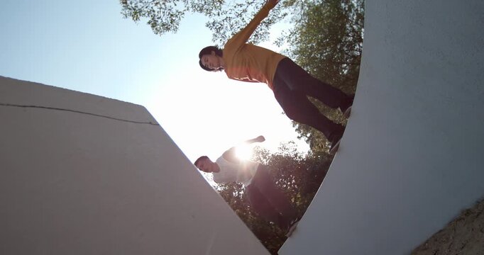 Cinematic time ramp enhances synchronized parkour leap of two athletes in 1000fps slow motion from low angle. Feel dynamic artistry of their urban flight in Bangkok. Concept: cinematic, synchronized