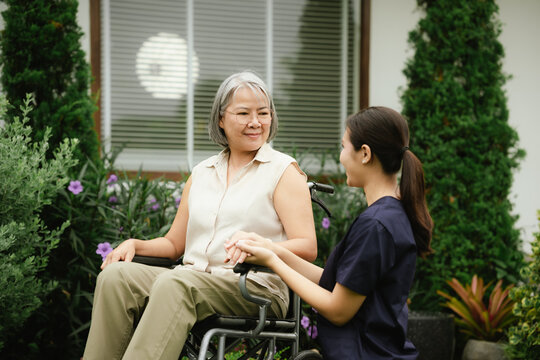 Professional caregiver assisting a senior woman in a wheelchair outdoors, promoting mobility, independence, and compassionate elderly care.