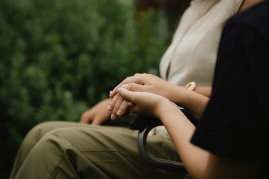 Professional caregiver assisting a senior woman in a wheelchair outdoors, promoting mobility, independence, and compassionate elderly care.