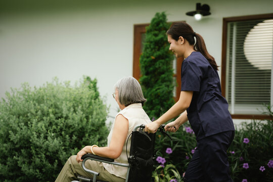 Professional caregiver assisting a senior woman in a wheelchair outdoors, promoting mobility, independence, and compassionate elderly care.