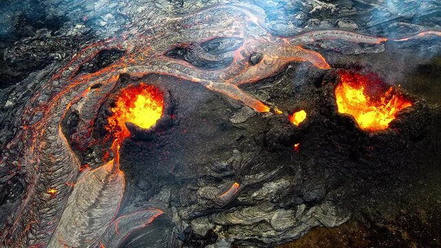 Molten lava flows down volcanic landscape with glowing orange and red rivers of fire and smoke.