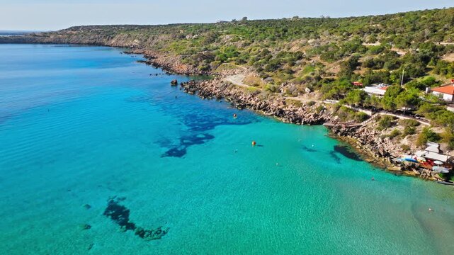 Aerial view of Konnos Bay, Cyprus. Calm blue water, sandy shoreline and green hills create a scenic coastal holiday view.