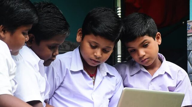 Rural Indian School Students Learning Digital Literacy on Laptop Computer Together. Indian Digital Education in Rural India: Group of Young Indian Boys Using Laptop.