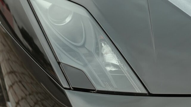 Close up of Lamborghini headlight lens and black hood curve