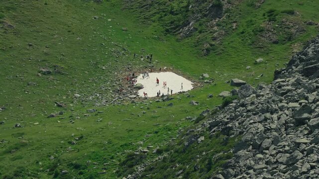Kids play on the last remaining patch of mountain snow, highlighting seasonal change, summer adventure and carefree fun in the mountains.
