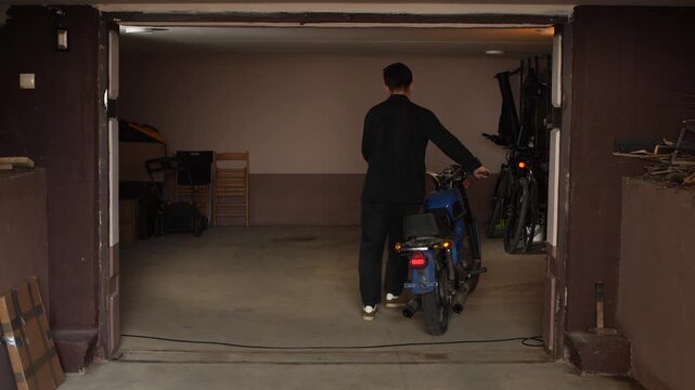 Man pushing classic blue motorcycle out of a home garage, ready for a ride, representing hobby, transportation, and retro lifestyle