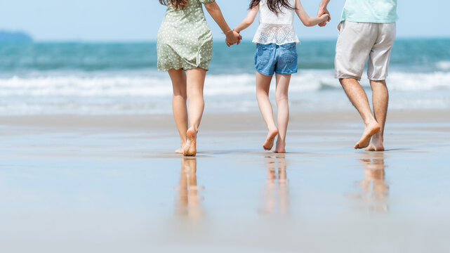 Parents and child walking barefoot along the shoreline embracing grounding through direct contact with nature promoting relaxation mindfulness and healthy outdoor living.
