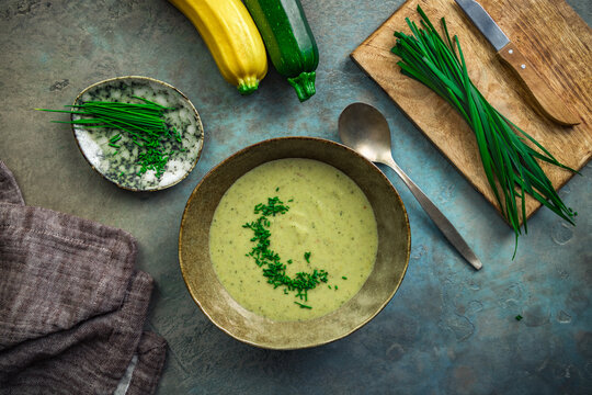 Creamy zucchini soup garnished with fresh chives served in a rustic bowl