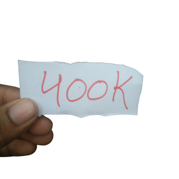 Hand holding a piece of torn white paper with the text 400k written in red ink isolated on transparent background