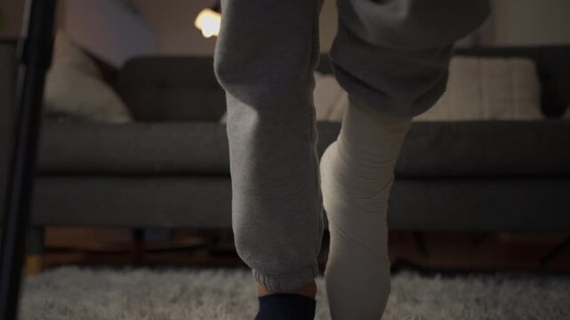Close-up of a person's injured leg with a plaster cast and crutches, slowly walking at home. A challenging recovery and rehabilitation process after an accident or injury