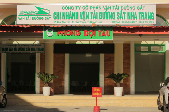NHA TRANG, VIETNAM - JANUARY 26, 2026: Entrance facade of a local train station passenger waiting room with Vietnamese text signage and potted palm trees.