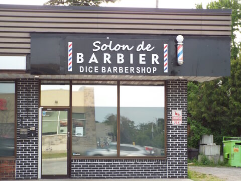 Gatineau,Quebec, Canada &ndash; May June 2, 2026:  A storefront featuring the "Solon de Barbier Dice Barbershop" sign with barber poles sits at 4 Rue Belmont.