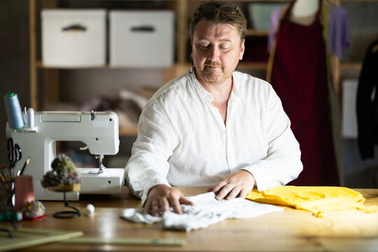 Middle-aged male dressmaker reviewing finished child dress