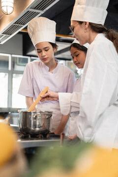 Chef Instructor Teaching Culinary Students How to Cook in a Pot During a Practical Cooking Class Inside a Modern Commercial Training Kitchen