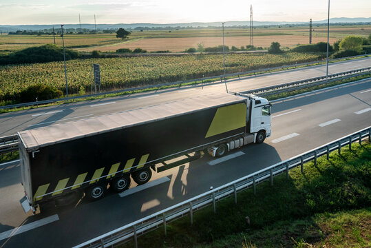 Transportation truck with semi-trailer driving along highway on the sunset background. Services and Transport logistics. Modern Lorry Transport concept. Long Self-driving lorries