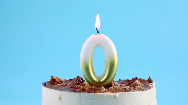 Number 0 birthday candle burning on cake. The zero birthday or anniversary celebration concept. Lot of copy space on blue background, studio shot. The concept of discount.