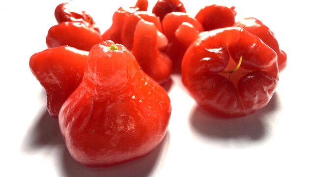 A pile of shiny red rose apples on a bright white background