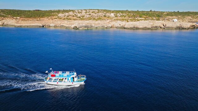 Aerial view of a boat sailing near Cavo Greco National Park in Cyprus. The bright blue sea and scenic coastline create a peaceful Mediterranean travel scene.