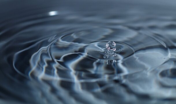 Macro Close Up of Water Droplet Impacting Liquid Surface Creating Ripples