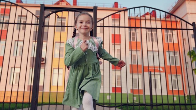 A little girl runs with a backpack from school dot. Happy little schoolgirl girl. A small child is happy that the lesson has ended. Children's running is a happy childhood. A childhood dream of a