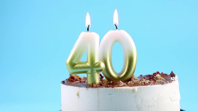 Number 40 birthday candle burning on cake. The fortieth birthday or anniversary celebration concept. Lot of copy space on blue background, studio shot.