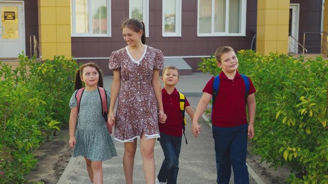 Morning routine at school, Siblings or friends together, Happy school memories, Protective adult with children, Fresh green plants, Accompanying kids to school, School entrance visible, Casual shoes