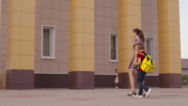 Children going to school in the morning, A family walking together, Kids carrying backpacks, Sunny day near the school, Parents guiding their children, School building in the background, Fresh start
