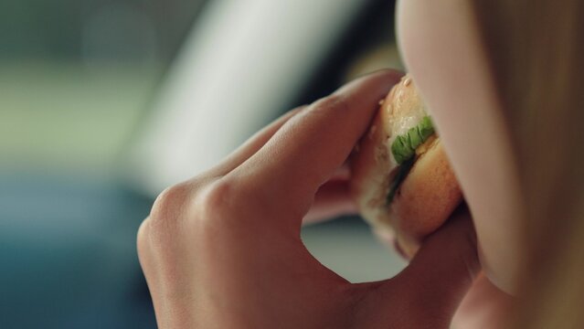 woman girl eating burger car, happy person, Young woman eats burger in car, Delicious hamburger close-up, Casual eating during drive, Food-to-go convenience, Satisfying cravings quickly, Lunch break