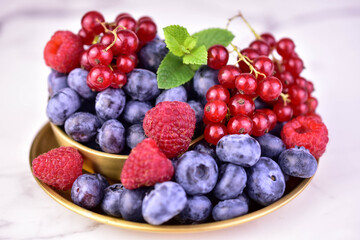 Assorted summer berries in a metal bowl on a white background. Close-up.  © Olivka888