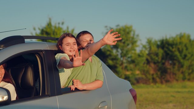 Woman mother child driving car, kid boy girl waving their hands out car window, happy family cheerful people childhood, country breeze blowing through car while children wave happily outside, playful