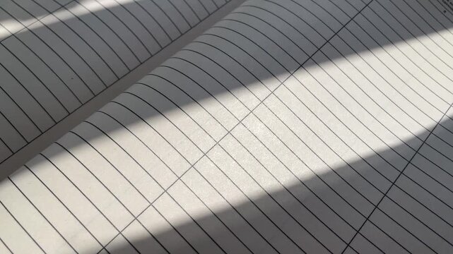 Lined Notebook Pages Flipping with Sunlight and Shadow Overlays - Education and Writing Concept. Close-Up