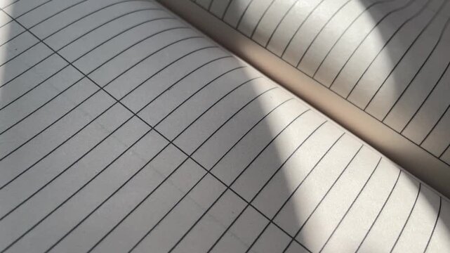 Lined Notebook Pages Flipping with Sunlight and Shadow Overlays - Education and Writing Concept. Close-Up