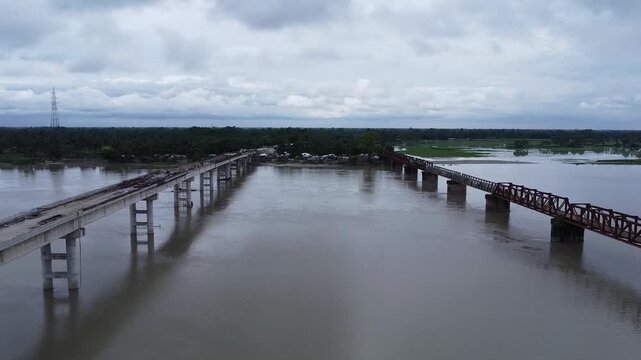 Aerial drone shot showing the contrast between an old iron bridge and a new bridge building project construction concrete truss river infrastructure construction concrete truss river