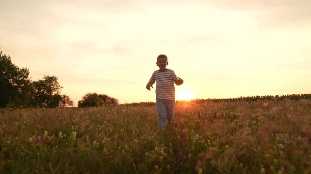 Boy running in a field at sunset, Child enjoying nature outdoors, Summer evening with golden sunlight, Happy kid playing in tall grass, Freedom and childhood memories, Peaceful countryside scene