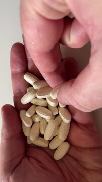 Man Holding Handful of Pills and Dietary Supplements Close Up