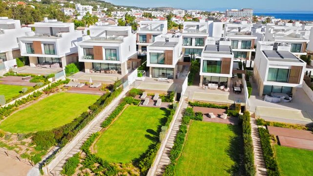 Aerial view of a resort near Konnos Bay, Cyprus. White buildings, green gardens and nearby coastline create a sunny seaside holiday scene.