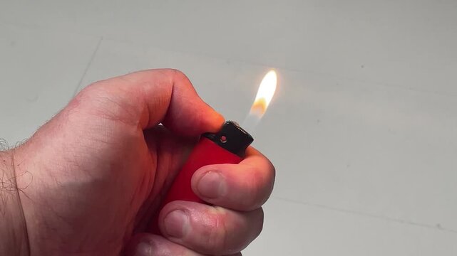 Hand Flicking and Igniting Red Plastic Lighter with Flame Burning Close-Up 